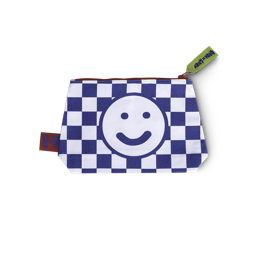 The Lush x Lazy wash bag, a white and navy blue checkered pattern, a happy face design with a green zipper tag and red accents.